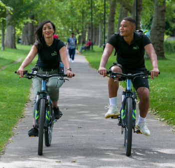 A man and a women cycle in a park