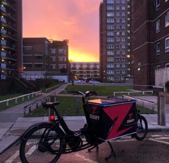 A large black and pink cargo bike with a box on the front that says 'Zedify' 