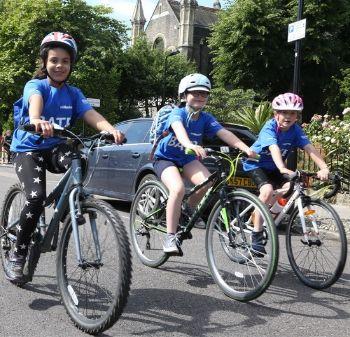 3 children cycle on a road 