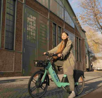 A woman poses in the sun with a blue TIER e-bike